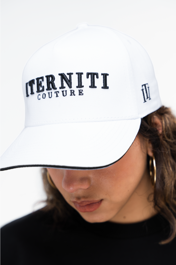 Mujer usando gorra blanca básica de Iterniti con ajuste en cuero. Estilo minimalista y urbano para cualquier ocasión