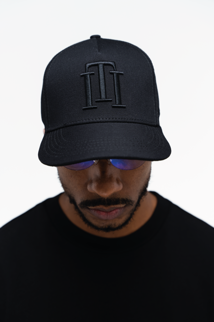 Vista frontal de la gorra negra de Iterniti con isotipo negro bordado, diseño minimalista y urbano
