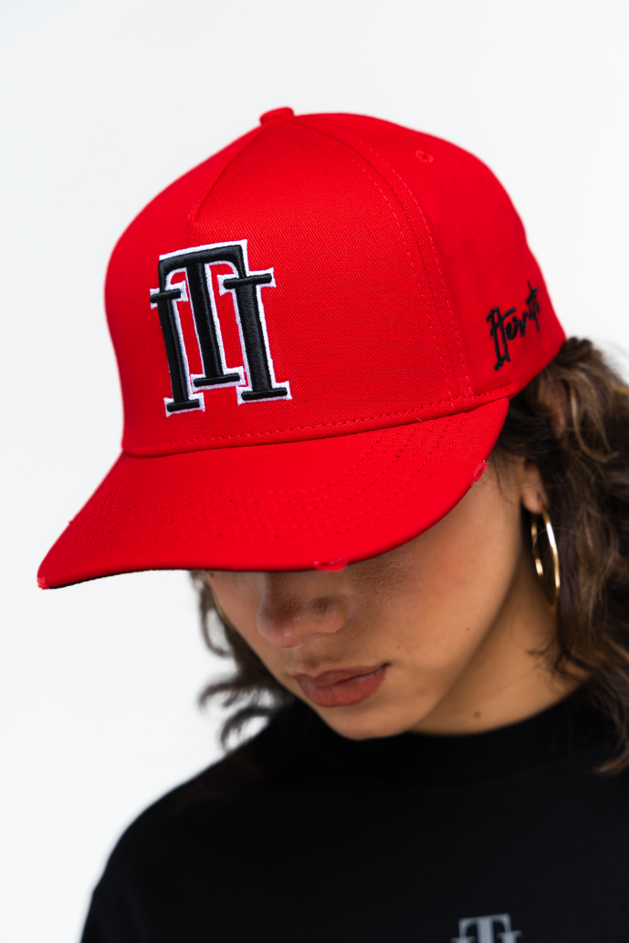 Detalle del isotipo bordado en la gorra roja de Iterniti, con contraste en negro y borde blanco para un acabado premium
