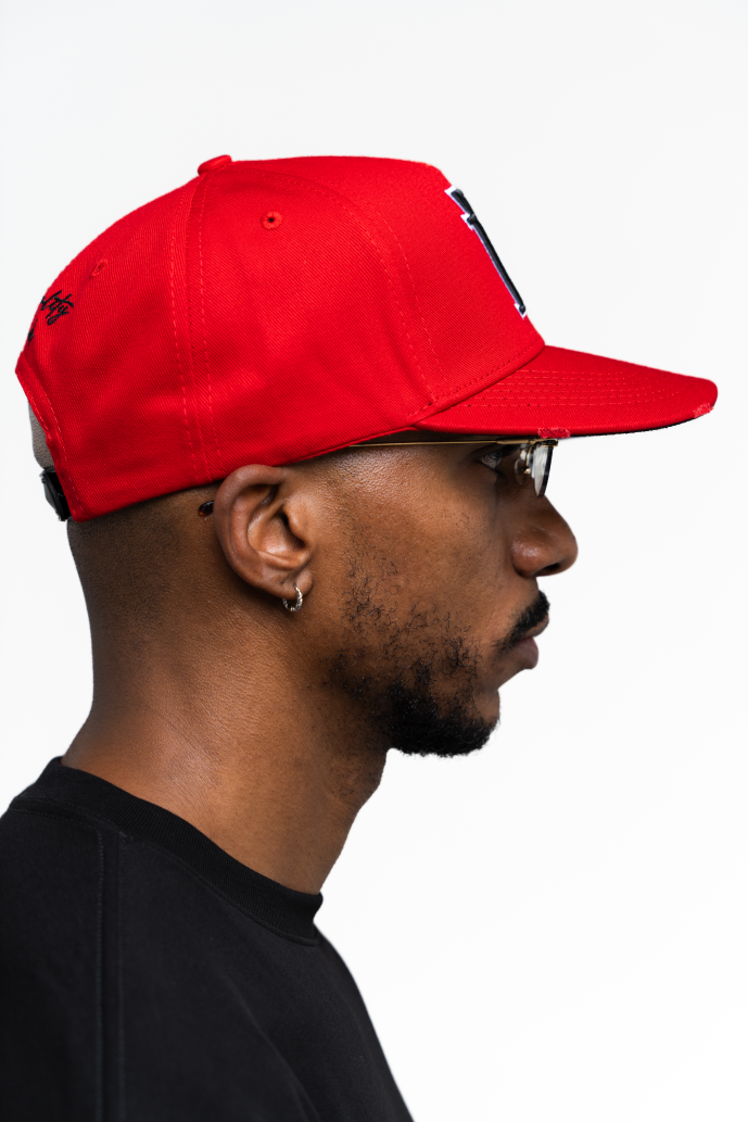 Vista lateral derecha de la gorra roja de Iterniti con isotipo negro y borde blanco, ideal para un look urbano