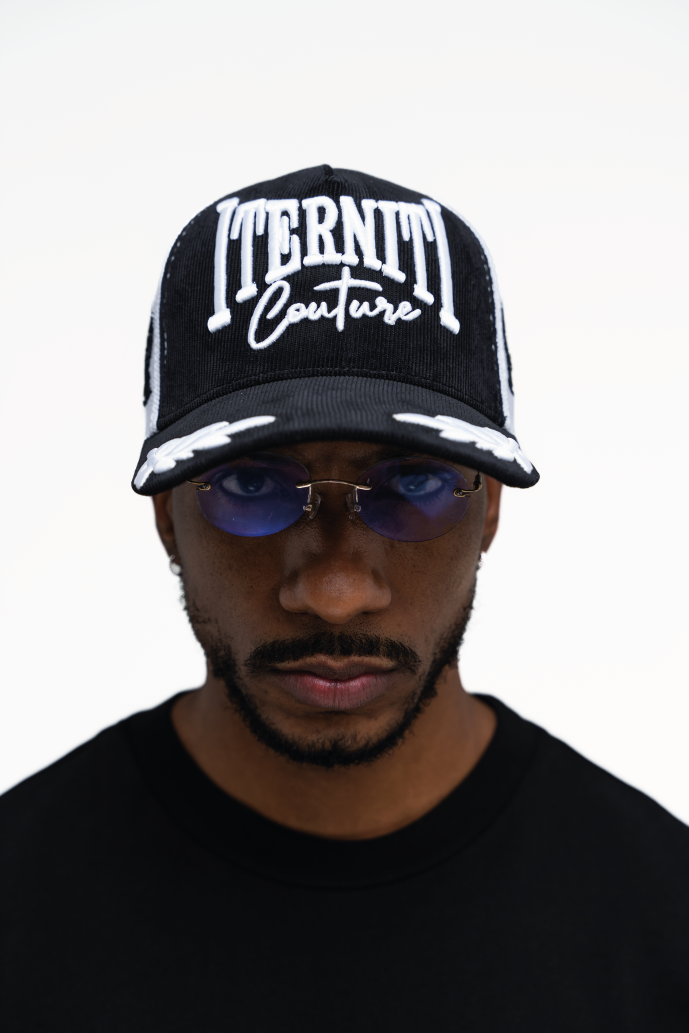 Gorra trucker blanca con detalles negros, diseño de aves y logo Iterniti bordado en el frente
