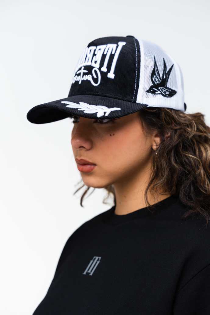 Vista lateral izquierda de la gorra trucker blanca con detalles negros y diseño urbano para mujer
