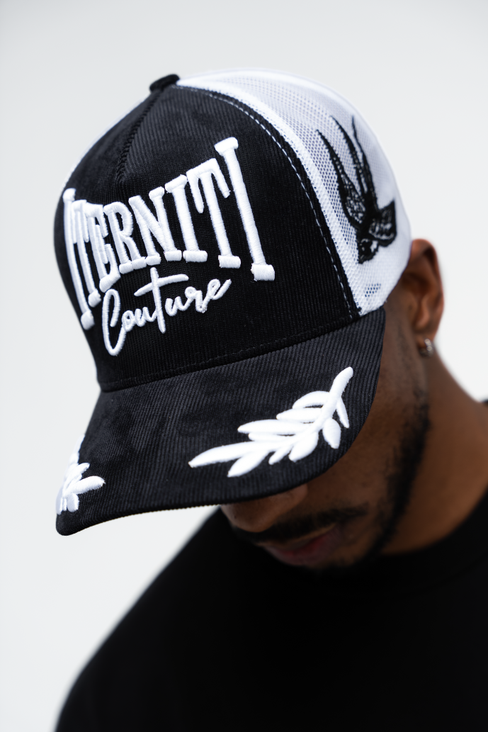 Primer plano del bordado de aves y la palabra Iterniti en la gorra trucker blanca, diseño único y moderno